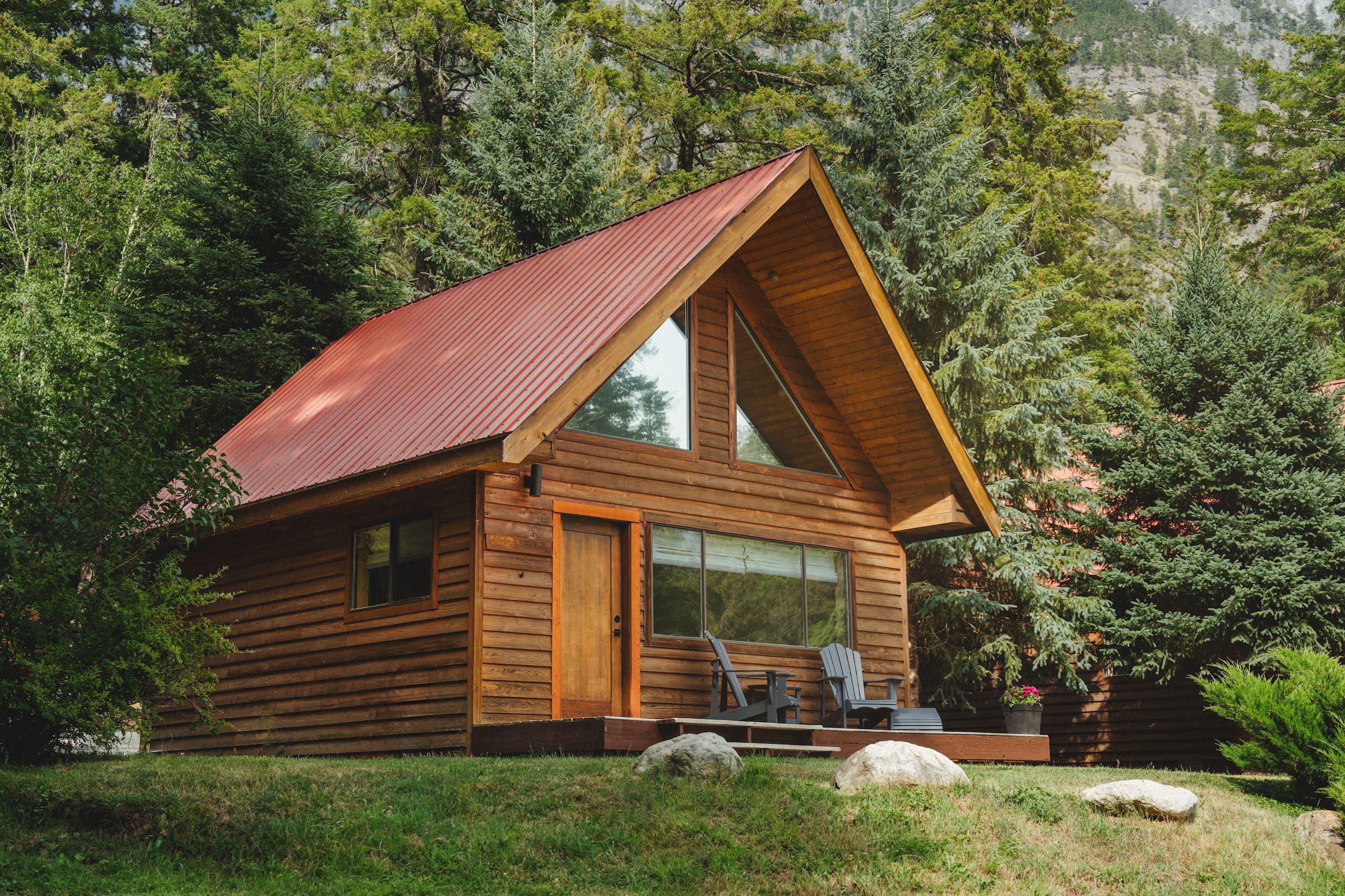 A Chalet in the woods with two chairs on the porch