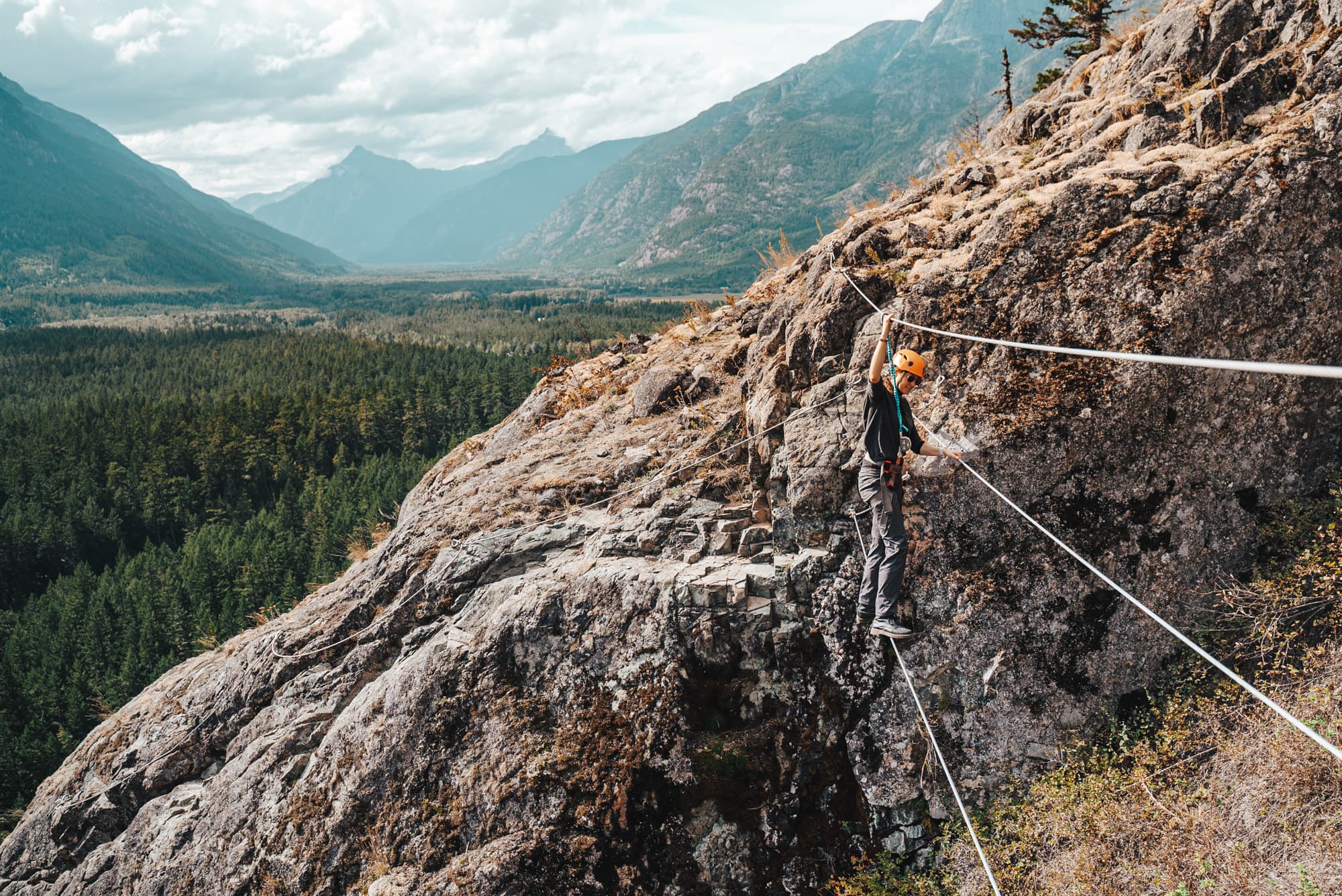 person balancing on a cable crossing a gap within the mountain