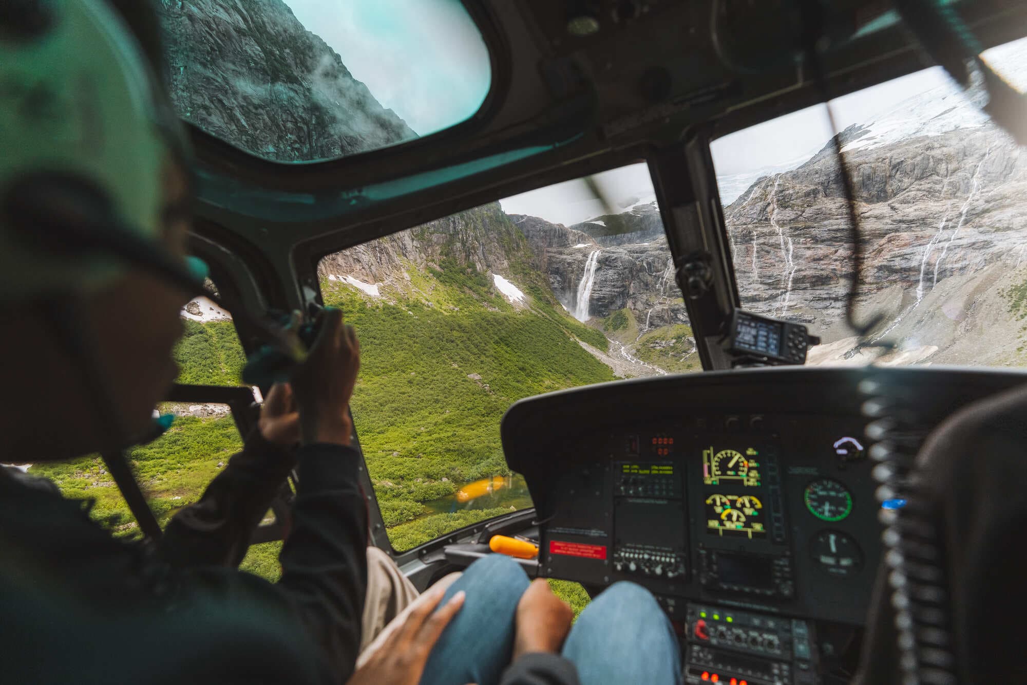 a view from inside a helicopter looking over green forest and mountains