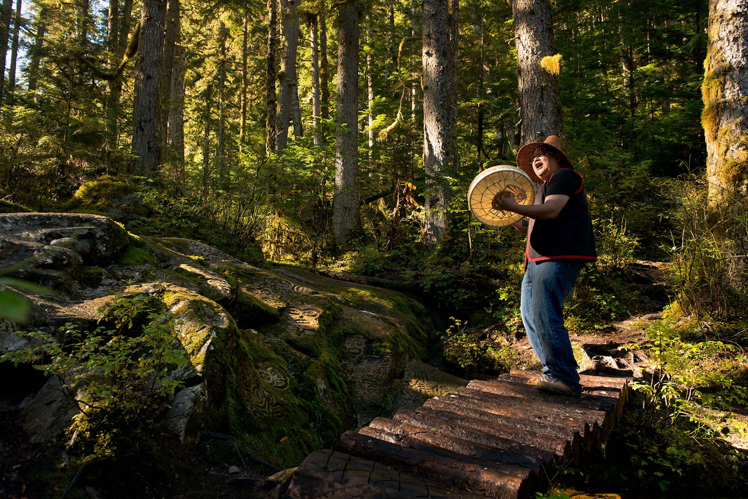A man playing a drum in the woods