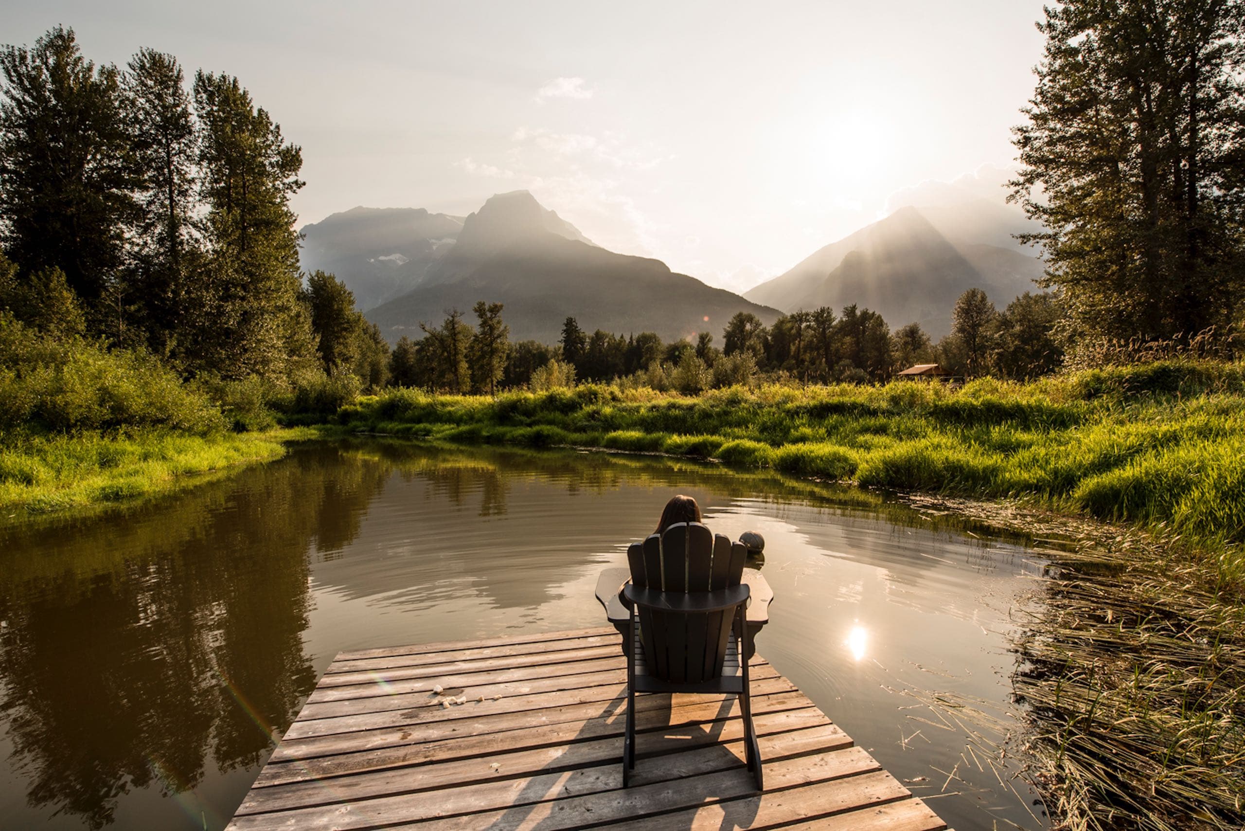 A woman sitting on a dock by a pond