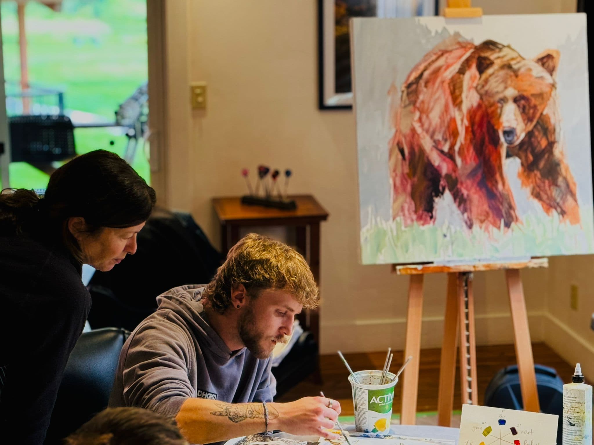 two men by a painting of a bear