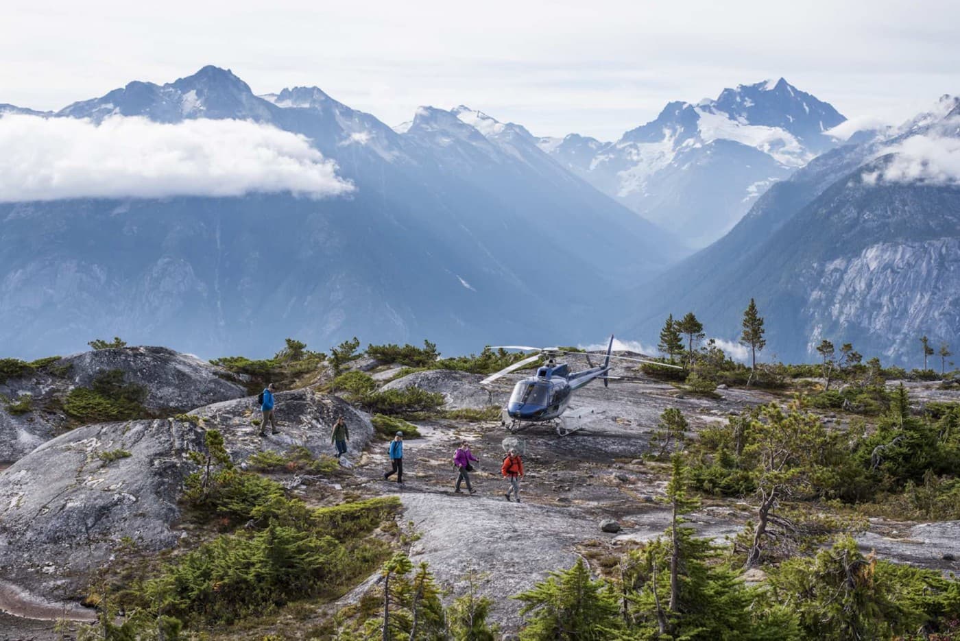 People on a mountain walking in front of a helicopter