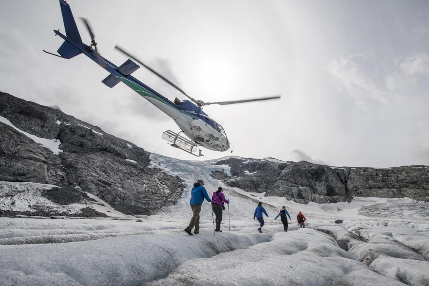 A group of people hiking on a mountain with a helicopter taking off